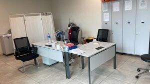 Office workspace with two desks, privacy screens, and filing lockers along the wall.