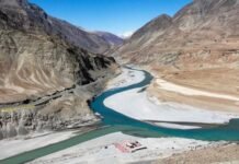 Facts Versus Fabrication: Reassessing the Indus Basin Water Debate Winding turquoise river through a desert canyon with tan mountains and white sediment on the banks, under a clear blue sky.