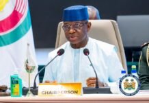 President Bio Delivers Landmark 69th ECOWAS Summit, Elevates Sierra Leone’s Regional Leadership Chairperson at a formal meeting, speaking into two microphones with a CHAIRPERSON nameplate in front of him.