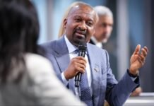 Vice President Leaves Hamburg Inspired by Shared Commitment to Sustainable Development and Global Cooperation Man in a blue suit speaks into a handheld microphone during a panel discussion, gesturing with his other hand, with a blurred figure in the background.