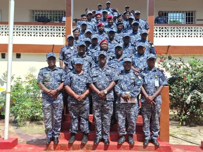 Group of military personnel in blue camouflage uniforms posing on red steps outside a building for a group photo.