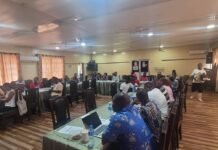 SLURC Engages Thompson Bay and Pamoronko Communities to Strengthen Climate-Resilient Land Use People seated around U-shaped conference tables in a meeting room, some with laptops and notebooks, a speaker standing at the back right.