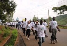 55 Runners Celebrate 55 Years of China–Sierra Leone Diplomatic Relations Group of people walking together on a paved road for a celebration, all wearing white T-shirts with a 55th anniversary design, countryside backdrop with hills and trees
