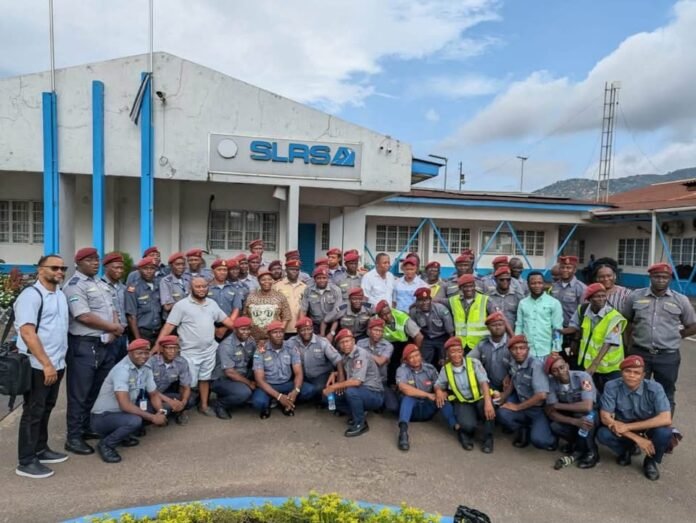 Group photo of uniformed officers with red berets posing outside a building labeled SLASA.