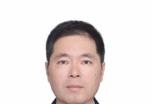 Serving the People, Safeguarding Peace… Celebrating the 99th Anniversary of the Founding of the Chinese People’s Liberation Army Professional headshot of a man in a dark suit and blue shirt, wearing a purple tie, facing the camera against a white background.