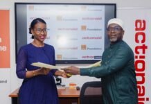 Orange Foundation and ActionAid Partner to Bridge Sierra Leone’s Digital Divide Two professionals exchange documents in an office setting with ActionAid Foundation branding in the background.