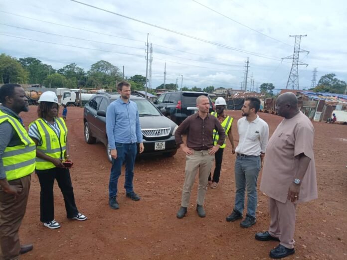 Group of professionals standing in a construction site, some wearing safety vests and hard hats, conversing near a parked SUV.