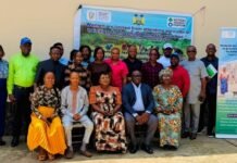 ACF, Partners Present Gender and Protection Analysis Findings to Guide Climate Adaptation Programme Group of men and women posing outdoors at a training event, with banners about women’s access to agricultural trainings in the background.