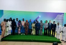 Government, UNDP and Africell Unveil UniPod Innovation Hub at Fourah Bay College Group of men and women in formal and traditional attire posing on a green stage in front of a colorful backdrop at a conference event.