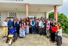 India High Commission Orients 50 ICCR Scholarship Awardees Ahead of 2026–2027 Academic Year Diverse group of men and women in business attire posing for a group photo outside a building, with a person in a wheelchair at the left foreground.