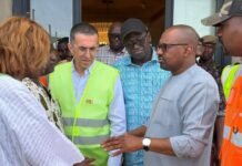 Vice President Inspects New International Conference Centre Ahead of ECOWAS Summit Group of officials in safety vests and casual shirts talking outside a doorway during a site visit.