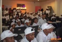 Africell American Corner Records Over 4,270 Users in Six Months, Expands Access to Free Learning Opportunities Group of trainees in a classroom using laptops, many wearing white caps, with Africell branding visible on walls and in the foreground.