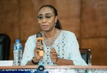 ICPNC Intensifies Drive for National Cohesion, Calls for Full Implementation of TRC Recommendations Panelist in a light blue embroidered outfit speaks into an orange-handled microphone at a Sierra Leone Ministry event, with a water bottle on the table nearby.
