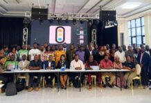 Tourism Ministry Strengthens Coastal Conservation Through Island and Beach Tourism Policy Initiative Large diverse group posing for a group photo in a conference room with a stage and digital display behind them on a pink logo screen.