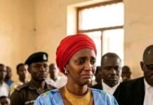 Zainab Sheriff Appeals for Alternative Sentencing, Better Welfare for Female Inmates Woman in blue traditional dress and red headwrap stands at the courthouse, teary-eyed and clasping her hands, Court No. 1 visible behind her.