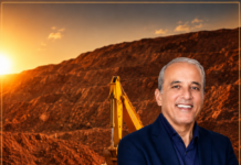 EXCLUSIVE: CTC Mining Fully Operational, Meets 100% Safety Compliance Standards Smiling man in a navy blazer with arms crossed at a construction site, excavator and dump truck behind him at sunset.