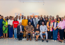 UNFPA, Government Review Progress of 8th Country Programme, Set New Targets Large diverse group of adults posing for a group photo in a conference room, with banners in the back indicating a formal event.