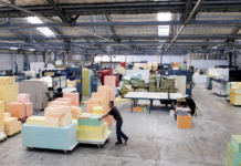 Fact Check: Independent Probe Clears Kings Foam Factory of Noise, Labour and Immigration Allegations Factory floor with stacks of colorful foam blocks on pallets and a worker pushing a cart to the left side of the image.