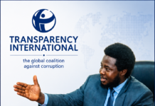 ACC, Transparency International Call on Sierra Leoneans to Embrace Integrity and Reject Corruption Man in a suit speaks at a Transparency International banner with a world map backdrop and TI logo on the left.