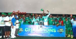 Group of players and staff posing with a trophy on a field, celebrating the banner reading 'LEONE PREMIER LEAGUE CHAMPIONS' and '50 RANGERS' in the background.