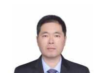 Tempered through 105 Years of Refinement and Forging Ahead: Reflections on the Journey of the Communist Party of China Portrait of a man in a dark suit and purple tie against a white background, professional headshot.