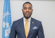 Advancing the AU Commitment: Accountability as the Pathway to Ending Harmful Practices in Sierra Leone Portrait of a man in a navy suit and yellow tie, with a UN flag in the background.