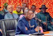 New Labour Minister Moves to Simplify Sierra Leone’s Labour Laws Man in blue traditional attire speaks into a microphone at a conference table, with colleagues seated behind him.