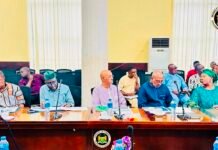 Finance Ministry Concludes Consultations on Revised Public Financial Management Act Government officials sit at a long conference table with microphones, water bottles, and papers during a formal meeting, banner and seal visible in the background.