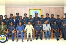 VP Juldeh Jalloh Chairs High-Level Police Meeting on Reform, Governance and National Security Formal group photo of police officers and officials, seated in front row with others standing behind in a conference room; portrait on the wall behind them.