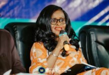 Higher Education Minister Calls for Tougher Action Against Examination Malpractice Woman in an orange patterned dress speaks into a microphone during a panel, logo of the Ministry of Information and Civic Education visible at the bottom.