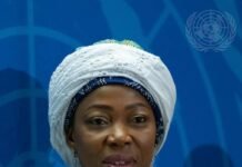 First Lady Fatima Bio to Present UN Resolution Against Child Marriage Portrait of a woman in a white lace headwrap and green‑blue embroidered dress at a United Nations event.