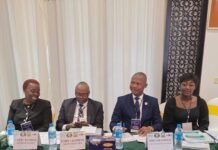 NPRA, UNEP and ECOWAS Advance Cleaner Fuel and Vehicle Standards in Sierra Leone Panel of four people seated at a table with name placards (UNEP/ECOWAS Representative, Director General) at a formal meeting; water bottles and documents on the table.