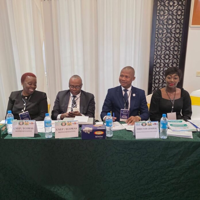 Panel of four people seated at a table with name placards (UNEP/ECOWAS Representative, Director General) at a formal meeting; water bottles and documents on the table.