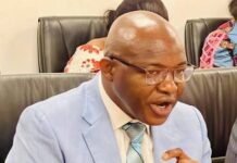 Weak GST Enforcement Costing Sierra Leone Billions—Majority Leader A man in a light blue suit and striped tie speaking, gesturing with his right hand in a meeting room.