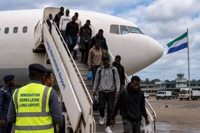 Group of travelers descending mobile stairs from a white airplane at Lungi Airport, Sierra Leone, with an immigration officer watching nearby.