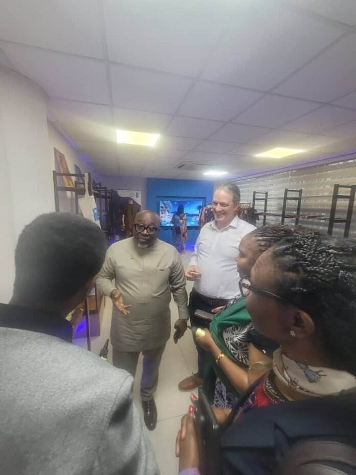 Group of five people standing in a bright store hallway, chatting and listening to a man in a beige outfit who is speaking.
