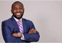 Sierra Rutile Executive Director: Sembehun Project to Position Sierra Leone Among World’s Leading Rutile Producers Smiling man in a navy suit with a pink striped tie, arms crossed, on a light gray background (professional portrait).