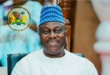 Parliament Ratifies SLNSA–Zhejiang Xiehai Agreement for Ocean Shipping Company Smiling man in white traditional clothing and a blue patterned cap, seated indoors with the Sierra Leone Ministry of Transport and Aviation seal in the corner.
