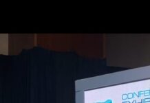 At Lagos Blue Economy Conference… Transport Minister Calls for Connected African Ports and Integrated Maritime Trade Man in light blue traditional attire delivering a keynote at a conference podium with multiple microphones; blue stage backdrop.