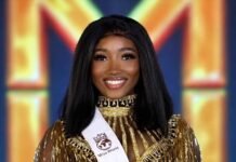 Miss Sierra Leone Mariyam Lorba Konneh Showcases Sierra Leone’s Beauty and Culture at Miss World 2026 in Vietnam Miss World contestant from Sierra Leone in a gold, beaded dress with a white sash, smiling on stage and holding a bouquet of white roses.