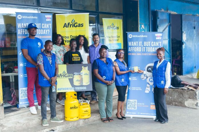 Group of smiling people posing with AfriGas banners and yellow gas cylinders outside a storefront?