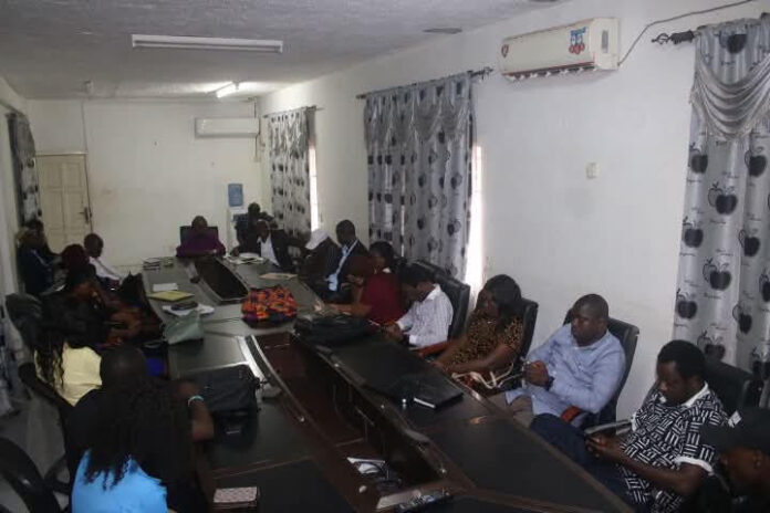 Group of professionals seated around a long conference table with laptops in a meeting room.