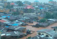 5,100 Flood-Affected Residents to Benefit from €175,000 EU Assistance A densely built hillside town submerged in muddy floodwater with houses and rooftops partially surrounded by water.
