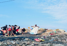 Living on the edge: WATERLOO BOMEH A DEATH TRAP Group of people standing and kneeling on a garbage dump under a blue sky, sorting through trash and debris.