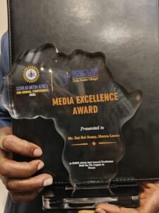 | The Calabash Newspaper Hand holds a clear trophy shaped like a map with orange text reading 'MEDIA EXCELLENCE AWARD' and 'Presented to Mr. Bai Bai Sesay, Sierra Leone' at a conference.