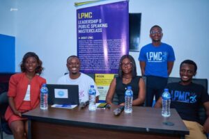 Five people sit at a conference table with water bottles; a purple LMPC banner stands behind them.