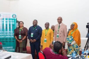 Six attendees pose for a group photo at a conference, banner visible on the left about risk communication in the background.