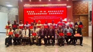 | The Calabash Newspaper Group of men and women pose with red certificates at a formal ceremony in a room; a red banner with Chinese text is displayed behind them.