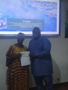 Two people standing side by side in front of a projector displaying No Signal; one holds a certificate.
