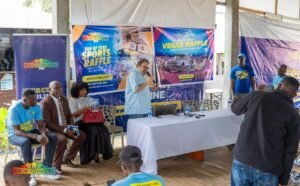 | The Calabash Newspaper Speaker with microphone at a raffle event, banners read End of Year Sports Raffle and Vegas Raffle by Mercury International.